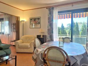 ein Wohnzimmer mit einem Tisch, Stühlen und einem Fenster in der Unterkunft Appartement Le Lavandou, 2 pièces, 4 personnes - FR-1-251-508 in Le Lavandou