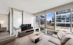 a living room with a couch and a large window at Lakefront Apartments Kingston ACT in Kingston 