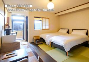 een kamer met 2 bedden, een bureau en een televisie bij Bihadanoyu Koshikano Onsen in Kirishima