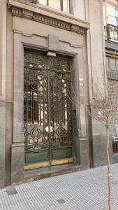 una puerta en un edificio con un árbol delante de él en Alquiler de habitación, con baño privado. en Buenos Aires
