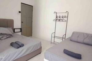 Un dormitorio con 2 camas y una silla. en Diamond Bay Homestay en Teluk Intan
