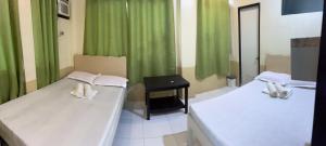 duas camas num quarto com cortinas verdes em Austrias Guest House em El Nido