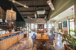 una mujer sentada en una mesa en un restaurante en Dugong Village-Green Hotel, en Pak Meng