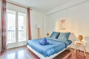 a bedroom with a blue bed and a large window at Appartement Quartier Saint Michel in Paris