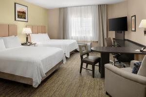 a hotel room with two beds and a desk at Candlewood Suites Turlock, an IHG Hotel in Turlock
