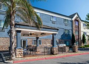 a large building with a porch and a palm tree at Candlewood Suites Turlock, an IHG Hotel in Turlock