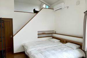 a bedroom with a white bed with two pillows at ADVENTURe (アドベンチャー) in Furano