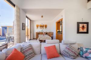 a living room with a white couch with colorful pillows at Villa de la Huerta con piscina privada y barbacoa in Güimar +16 photos