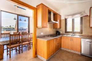 uma cozinha com armários de madeira e uma sala de jantar com uma mesa em Villa de la Huerta con piscina privada y barbacoa em Güímar