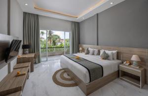 a bedroom with a large bed and a television at Tapa Tepi Kali Canggu in Canggu