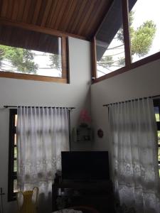 モンテ・ヴェルデにあるRefúgio dos Sonhos - Casa nas Montanhas - Monte Verdeの白いカーテンがかかったリビングルームの2つの窓