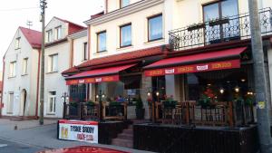 a restaurant with red awnings on a city street at Pokoje gościnne vis a vis Retro in Gostynin