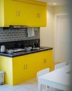 una cocina con armarios amarillos y fregadero en Emerald Manor Hotel en Kababae
