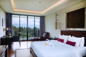 a hotel room with a large bed and a balcony at Handara Golf & Resort Bali in Bedugul