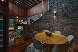 ein Esszimmer mit einem Holztisch und einer Ziegelwand in der Unterkunft Summer of 81 I Private Properties in Vasse + 25 Fotos