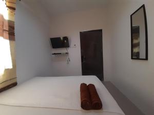 a bedroom with a white bed with two brown shoes on it at Capital O 93076 Batam Backpacker Guesthouse 2 in Pembunuh