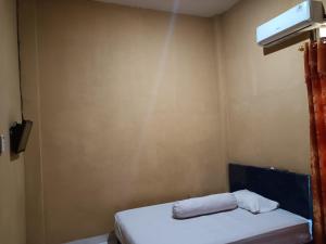 Habitación pequeña con cama y ventilador. en OYO 93073 Penginapan 69, en Jayapura
