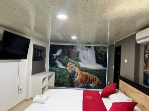 een slaapkamer met een schilderij van een tijger in het water bij Hotel Entre Parques in La Dorada