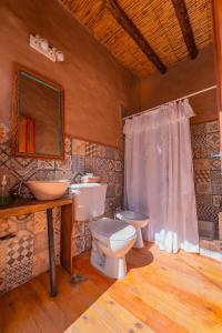a bathroom with a toilet and a sink and a mirror at Cabaña Misk'i Nuna, en las afueras de Tilcara in Tilcara