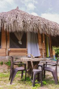 a group of chairs and a table in front of a hut at Magic Green Dentro del Parque Tayrona in El Zaino