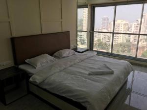 a bed with two pillows on it in a room with windows at Ocean View Luxury Designer condo in Mumbai