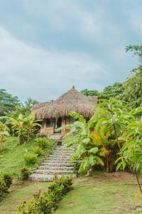a house with a thatched roof with stairs leading to it at Magic Green Dentro del Parque Tayrona in El Zaino