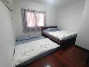 two twin beds in a room with a window at Journey House Bangsean in Ban Laem Thaen