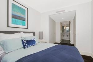 a bedroom with a large bed with a blue blanket at The Prince Lakefront Kingston ACT in Canberra