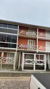 een rood gebouw met ramen en een auto voor de deur bij Apartamento Dúplex in Cidreira