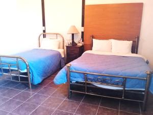 a bedroom with two beds with blue sheets at Hotel Vitorina in Atlixco