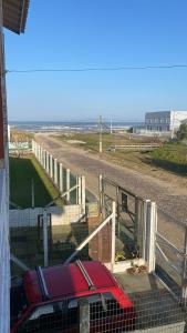 een rode auto staat geparkeerd naast een hek bij Apartamento Dúplex in Cidreira