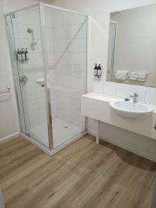 a white bathroom with a shower and a sink at Captains Cove Resort - Waterfront Apartments in Paynesville +42 photos
