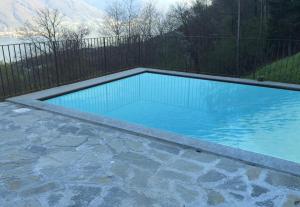 een zwembad met blauw water en een hek bij Villa Aquila in Pianello Del Lario