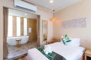 a bedroom with a tub and a bed and a bath room at Vannee Golden Sands Beachfront Resort in Haad Rin