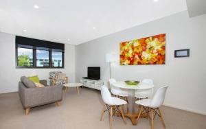 ein Wohnzimmer mit einem Sofa, einem Tisch und Stühlen in der Unterkunft IQ Smart Apartments Braddon ACT in Canberra