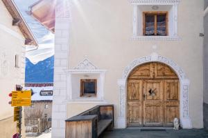 - un bâtiment avec une grande porte en bois et un escalier dans l'établissement Chasa Sömmi, à Ftan