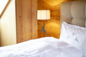 een bed met witte lakens en een lamp in een kamer bij Chasa Sömmi in Ftan