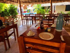 a wooden table with a plate on it in a restaurant at Mkeka Spice Lodge Jambiani in Jambiani