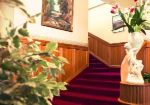 um corredor com escadas com uma planta e uma pintura em The County Hotel em Napier