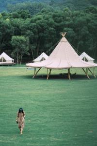 um homem andando por um campo com uma tenda em NatureLand Campsite em Shenzhen