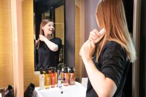 a woman brushing her hair in front of a mirror at HOTEL Cargo Shinsaibashi in Osaka