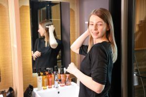 a woman standing in front of a bathroom mirror at HOTEL Cargo Shinsaibashi in Osaka