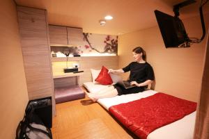 a woman sitting on a bed in a room at HOTEL Cargo Shinsaibashi in Osaka