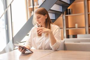 a girl sitting at a table reading a book at HOTEL Cargo Shinsaibashi in Osaka