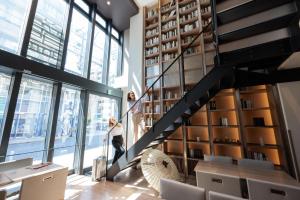 two people walking up a staircase in a room with windows at HOTEL Cargo Shinsaibashi in Osaka