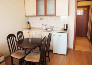 a kitchen with a table and a white refrigerator at PM Services Flora Apartments in Borovets