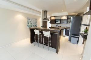 a kitchen with a bar with stools in it at The Pearls 4th Floor Luxury Apartment with inverter in Summerstrand