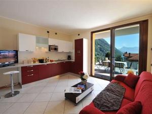 Il comprend un salon avec un canapé rouge et une cuisine. dans l'établissement Residence Eden Apartments, à Argegno