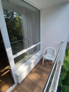 une chaise blanche assise sur un balcon avec fenêtre dans l'établissement Apartament 20 Ula, à Ustroń
