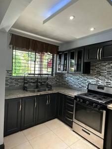 a kitchen with black cabinets and a stove top oven at The Jewel in Kingston